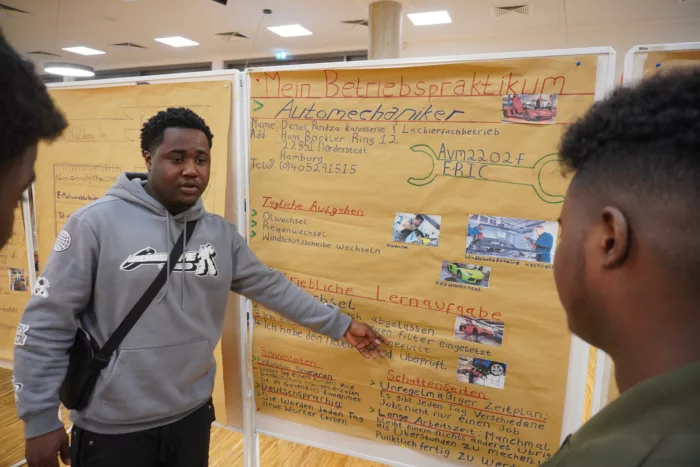 Schüler vor einer Metaplanwand mit einem selbstgestalteten Plakat.