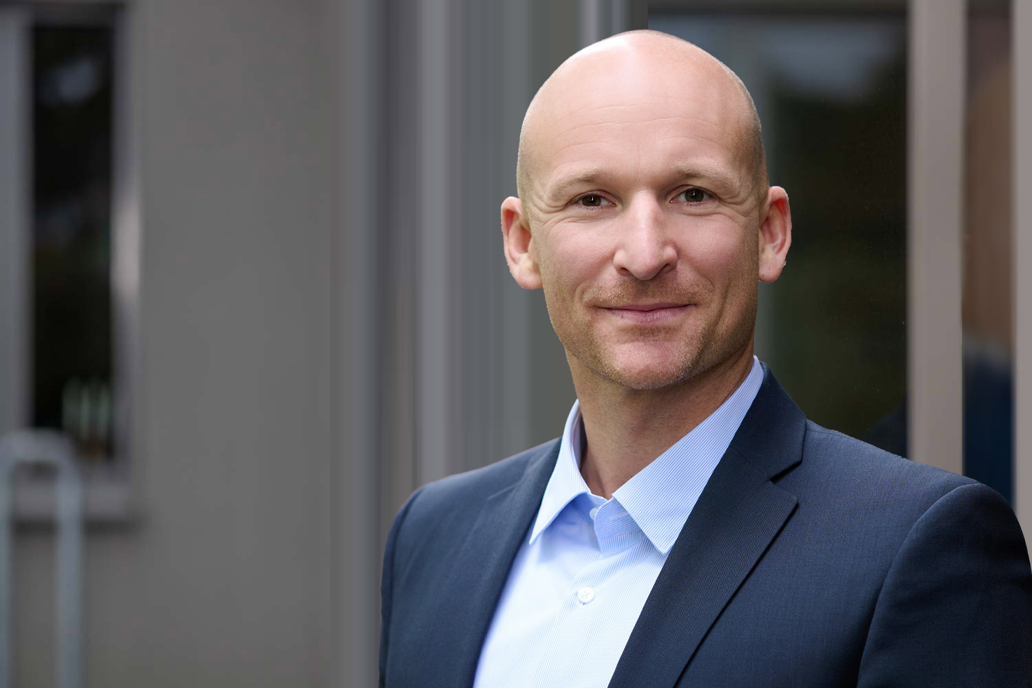 Portraitfoto von Malte-Baumann, Schulleiter. Er steht vor einem Fenster.